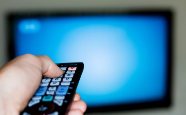 a person switching the tv on using a remote control