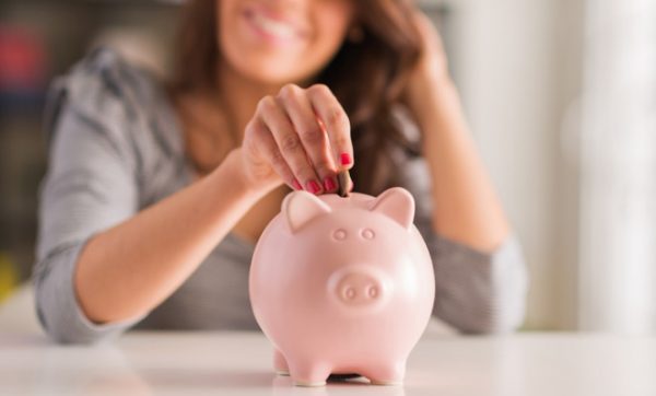 a woman dropping money in a piggy bank