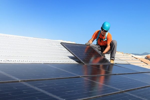 a handyman installing solar panels on a roof