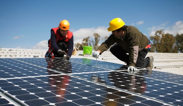 Two handymen installing solar panels on a roof